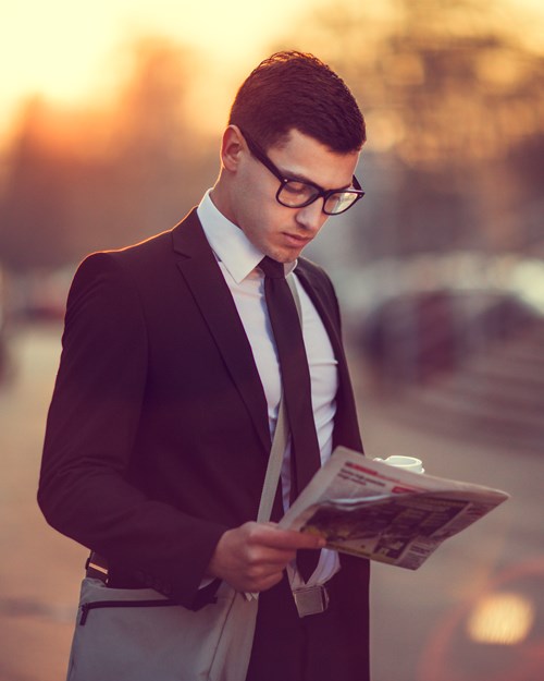 Business man with coffee reading newspaper