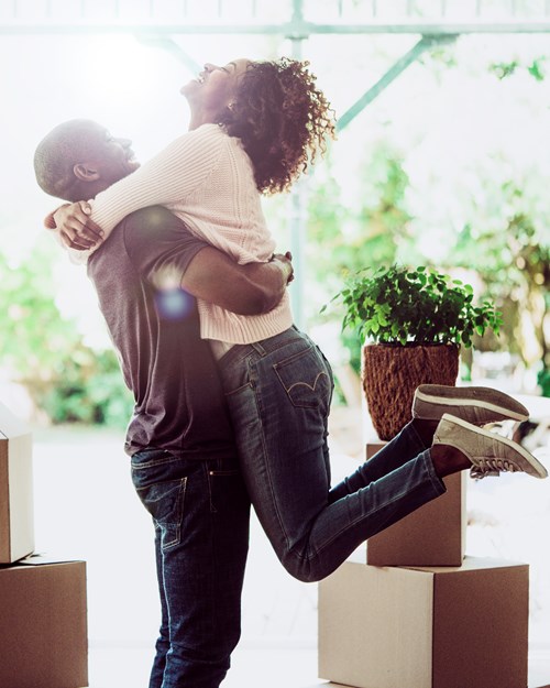 Happy man lifting woman in their new house