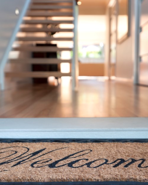 Close up of a welcome mat and an inviting house