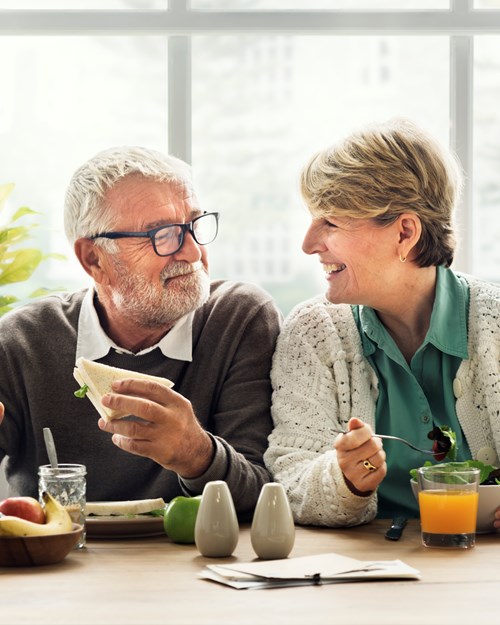 Elderly couple smiling eating lunch